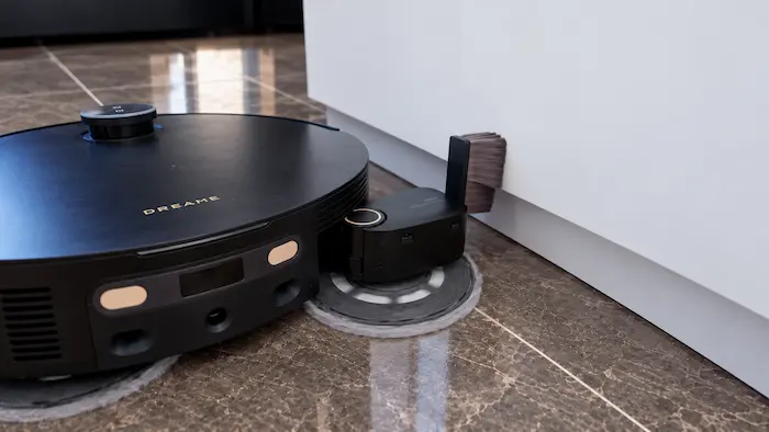 Bras UltraExtend du Dreame X60 déployé vers le bord d’un meuble